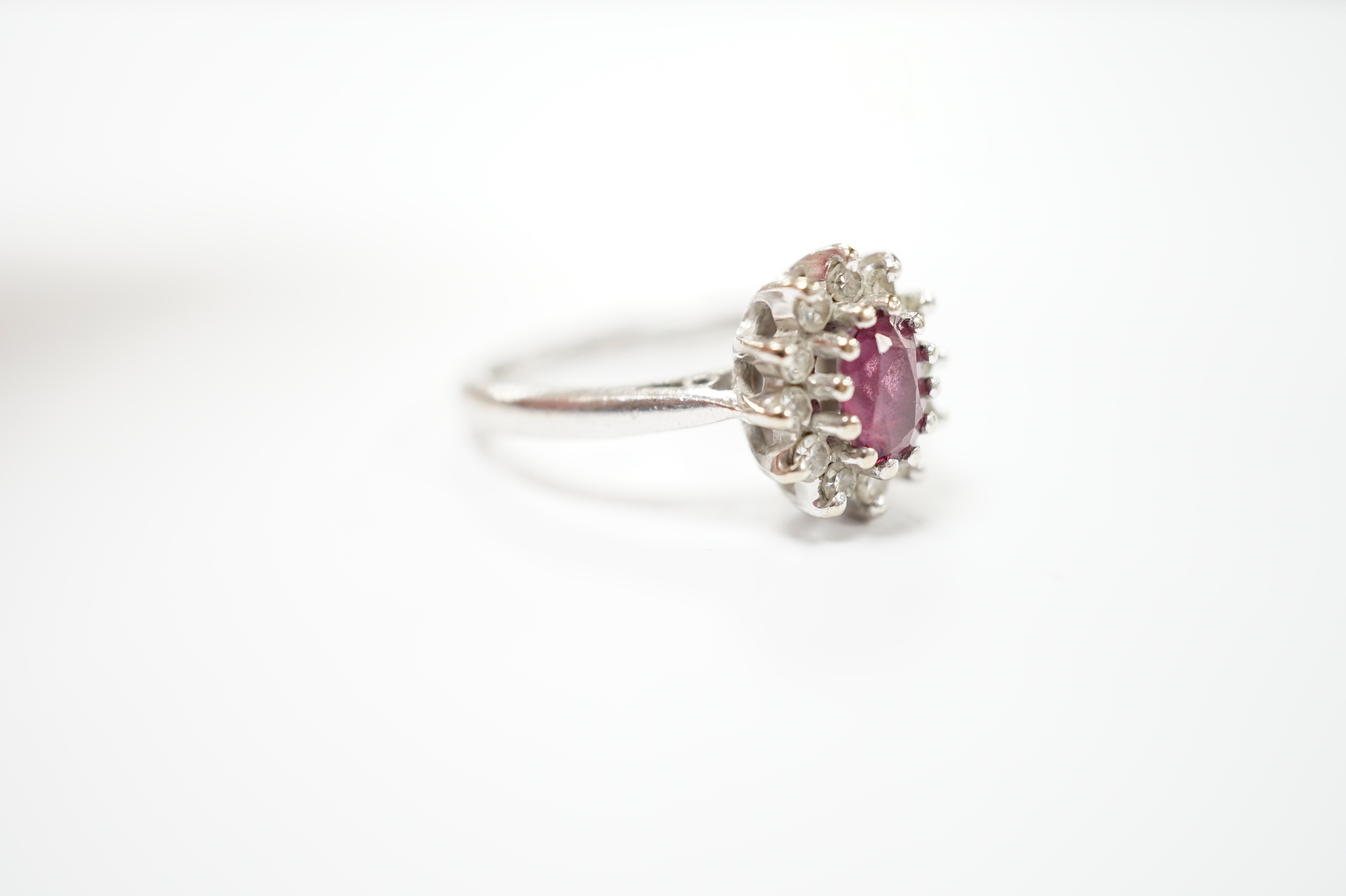 A modern 18ct white gold, ruby and diamond set oval cluster ring, size M/N, gross weight 5.2 grams.